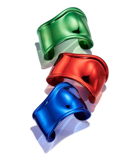Three shiny metallic cuff bracelets in green, red, and blue, arranged diagonally against a white background.