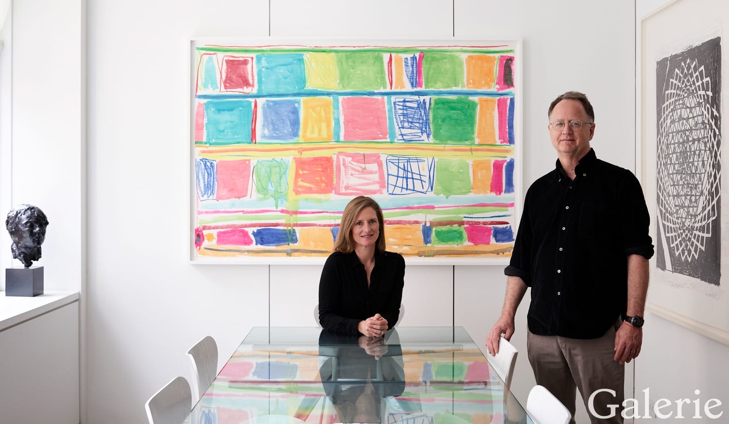Two people in a modern art gallery with colorful abstract paintings on the wall and a sculpture on a stand.