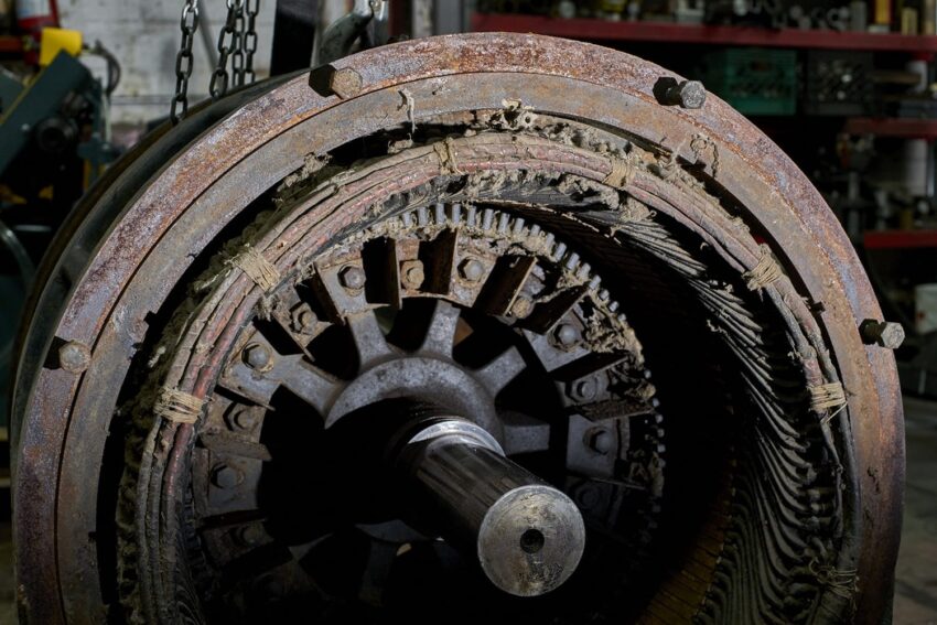 Close-up view of an old, rusty industrial machine part with intricate details and exposed components in a workshop setting.