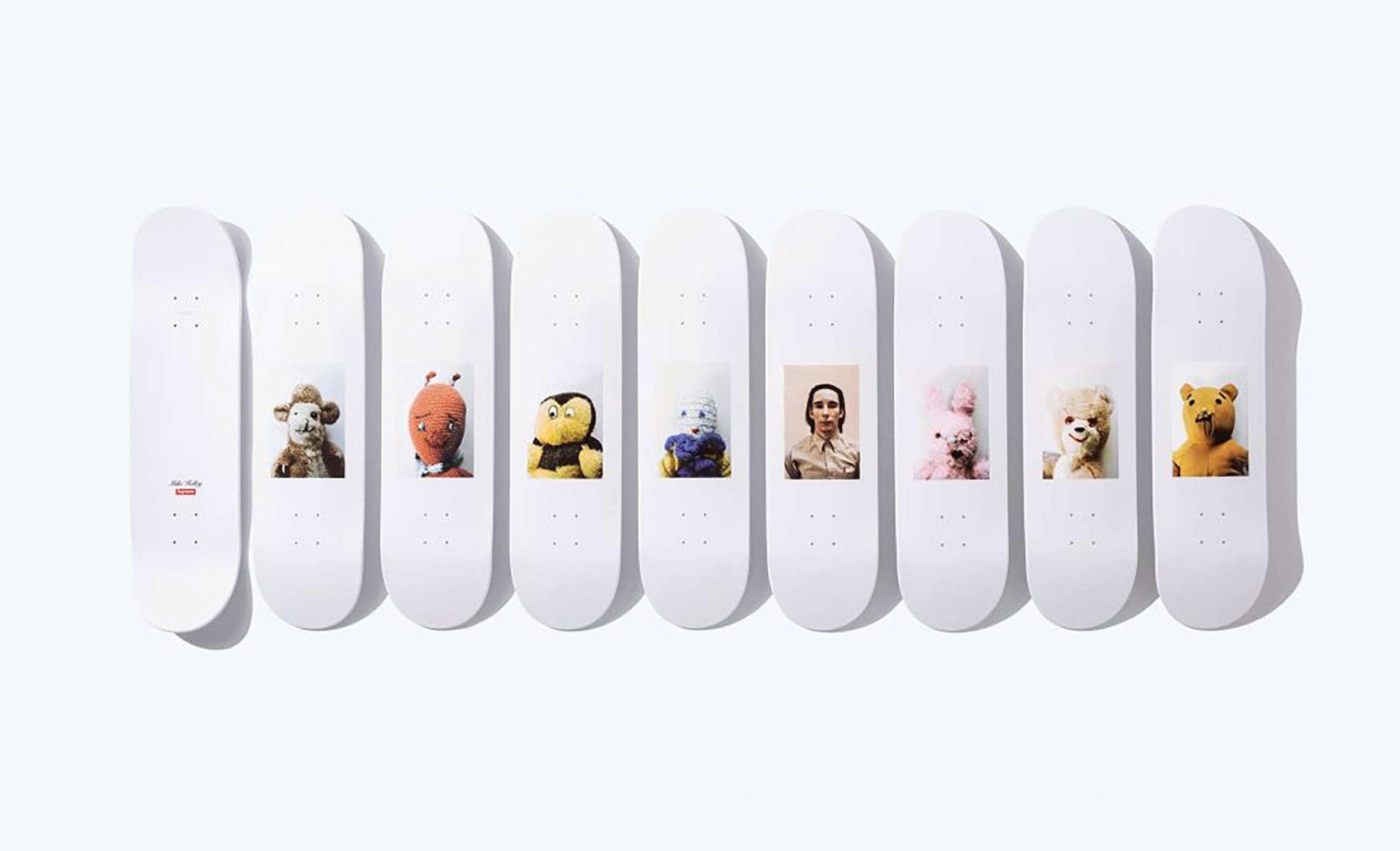 Nine skateboard decks featuring various colorful character designs aligned in a row against a plain background.