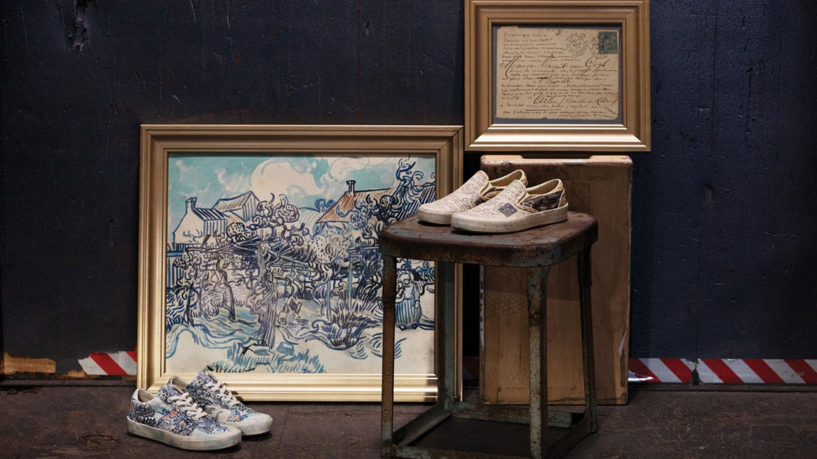 Framed artwork and vintage sneakers displayed on a stool and crate against a dark wall in an artistic setup.