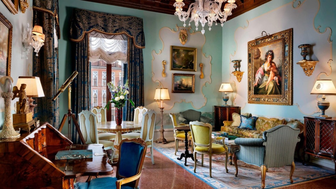 Elegant vintage living room with chandelier, antique furniture, ornate paintings, telescope by window, and rich decor.