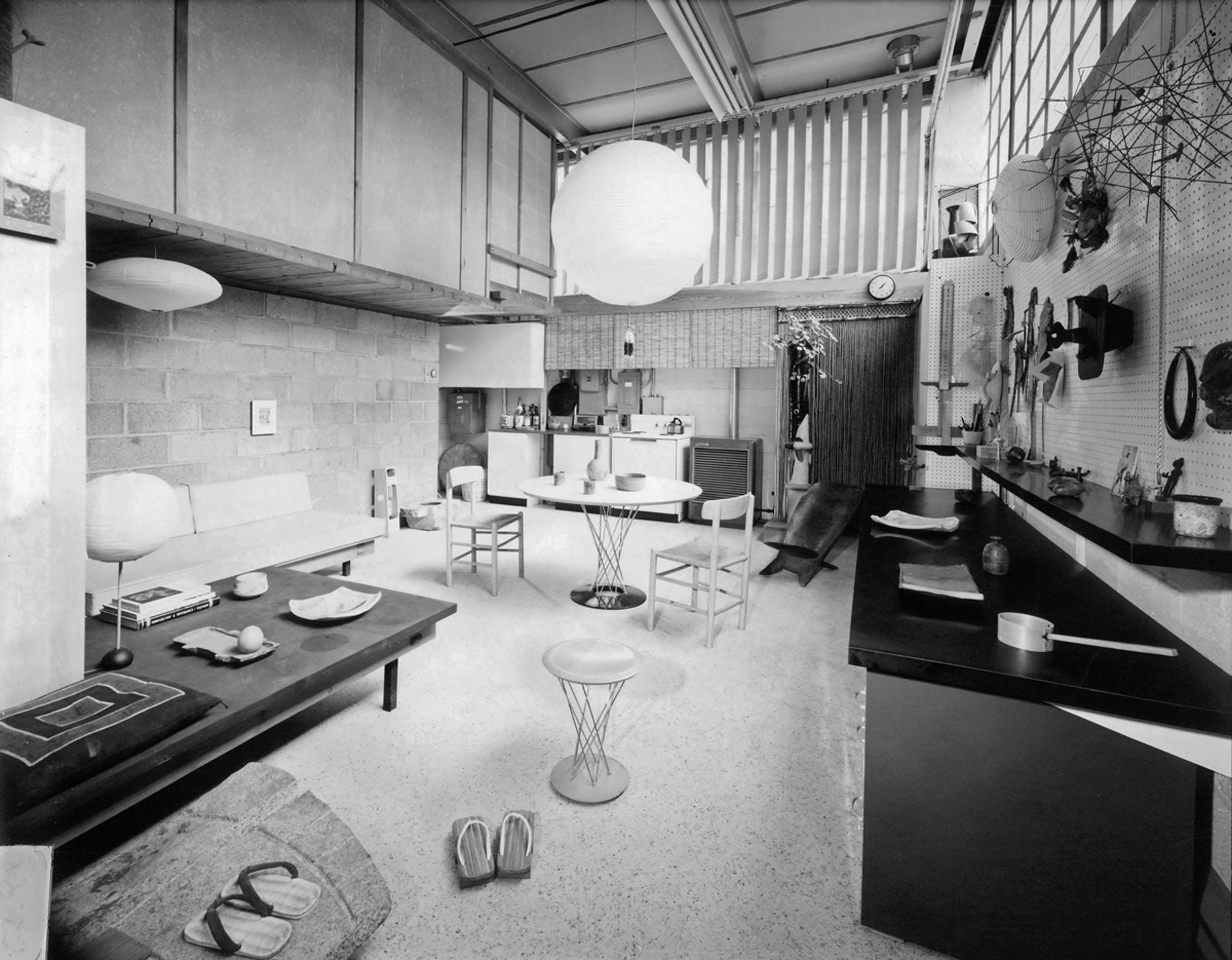 Mid-century modern living room with dining area, featuring minimalist furniture, spherical lamp, and eclectic decor.