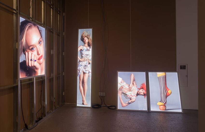 Art installation with illuminated portraits and creative poses displayed on screens against an unfinished wall background.