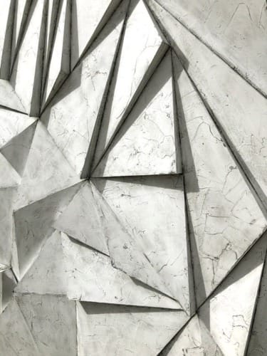geometric 3D wall with triangular shapes and a textured concrete appearance
