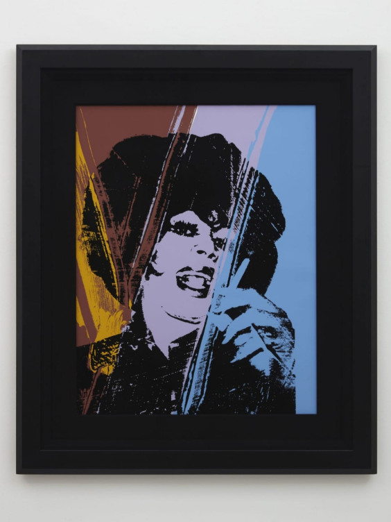 Colorful pop art portrait in a black frame against a plain wall background.