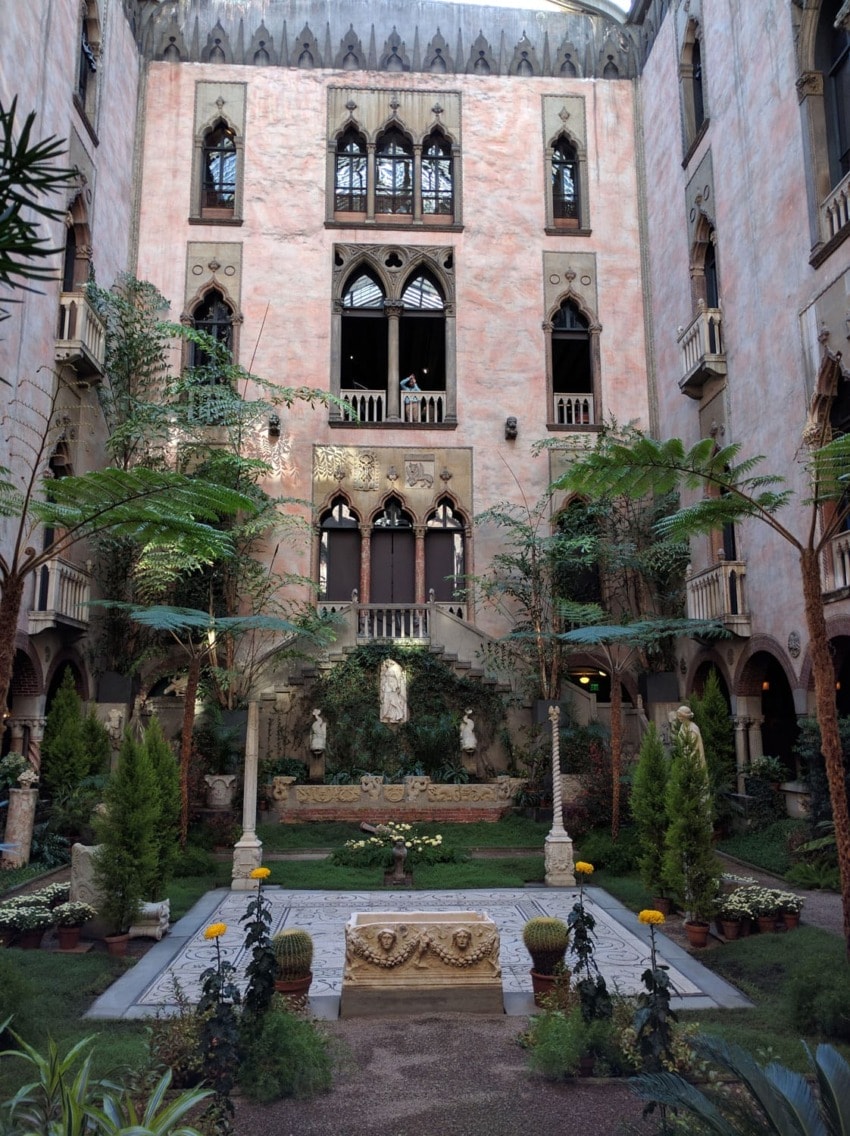 Interior courtyard with lush greenery, statues, and ornate architectural details in a historic building.