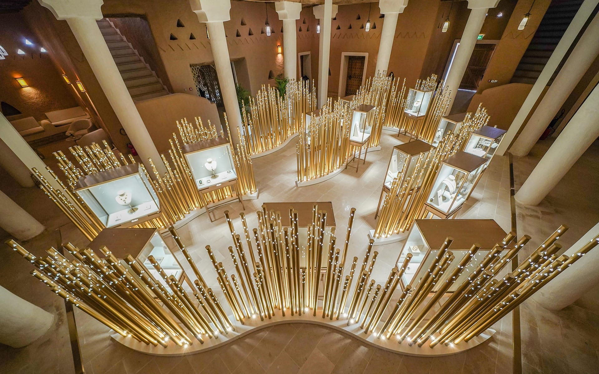 Modern architectural interior with golden vertical rods and illuminated display cases surrounded by columns in a circular layout.