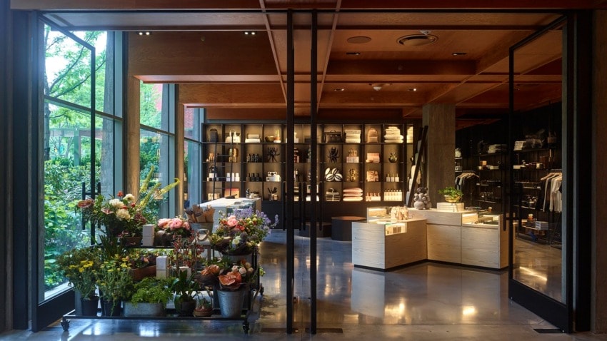 Modern shop interior with large windows, shelves of products, and vibrant floral display in the foreground.