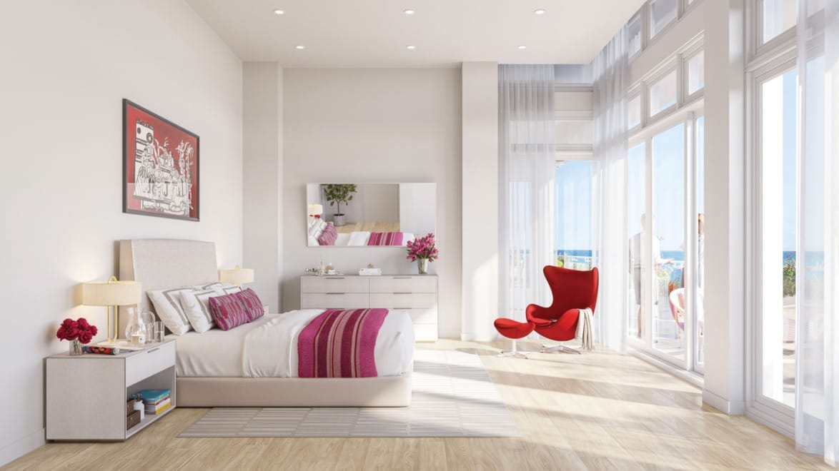 Modern bedroom with large windows, stylish red chair, and pink accents. Bright and airy with natural light and ocean view.