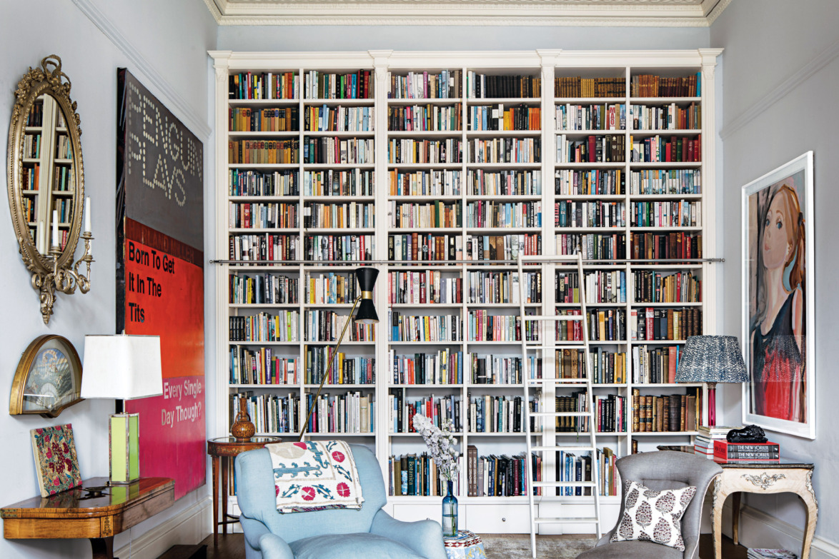 Cozy living room with a large bookshelf filled with books, a comfortable chair, and decorative lampshades.
