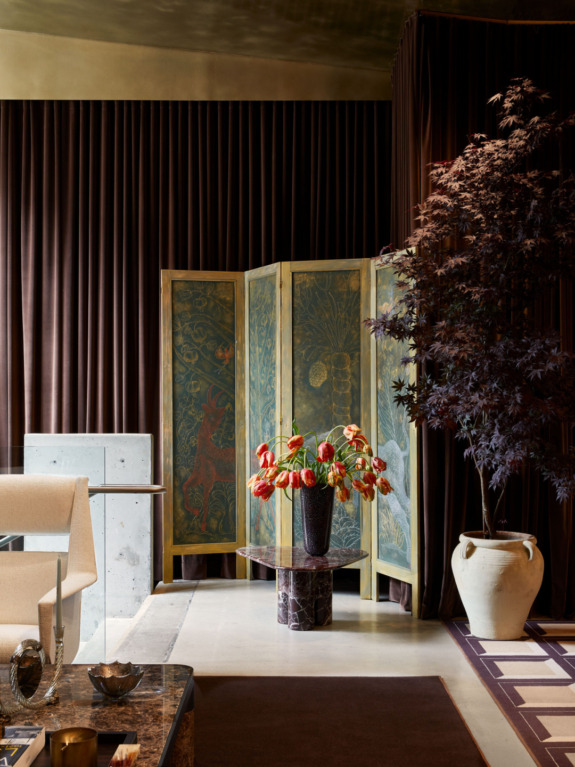 Elegant interior with a panel screen, potted plant, and a centerpiece of vibrant flowers on a marble table.