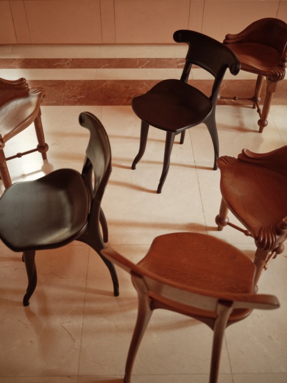 Wooden chairs arranged in a circle on a marble floor with soft lighting creating a warm and inviting atmosphere.