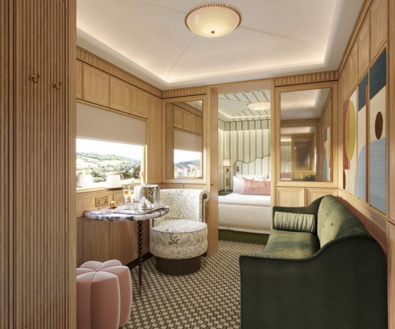 Elegant train cabin interior with cozy seating, a small table set with refreshments, and a view of the countryside.