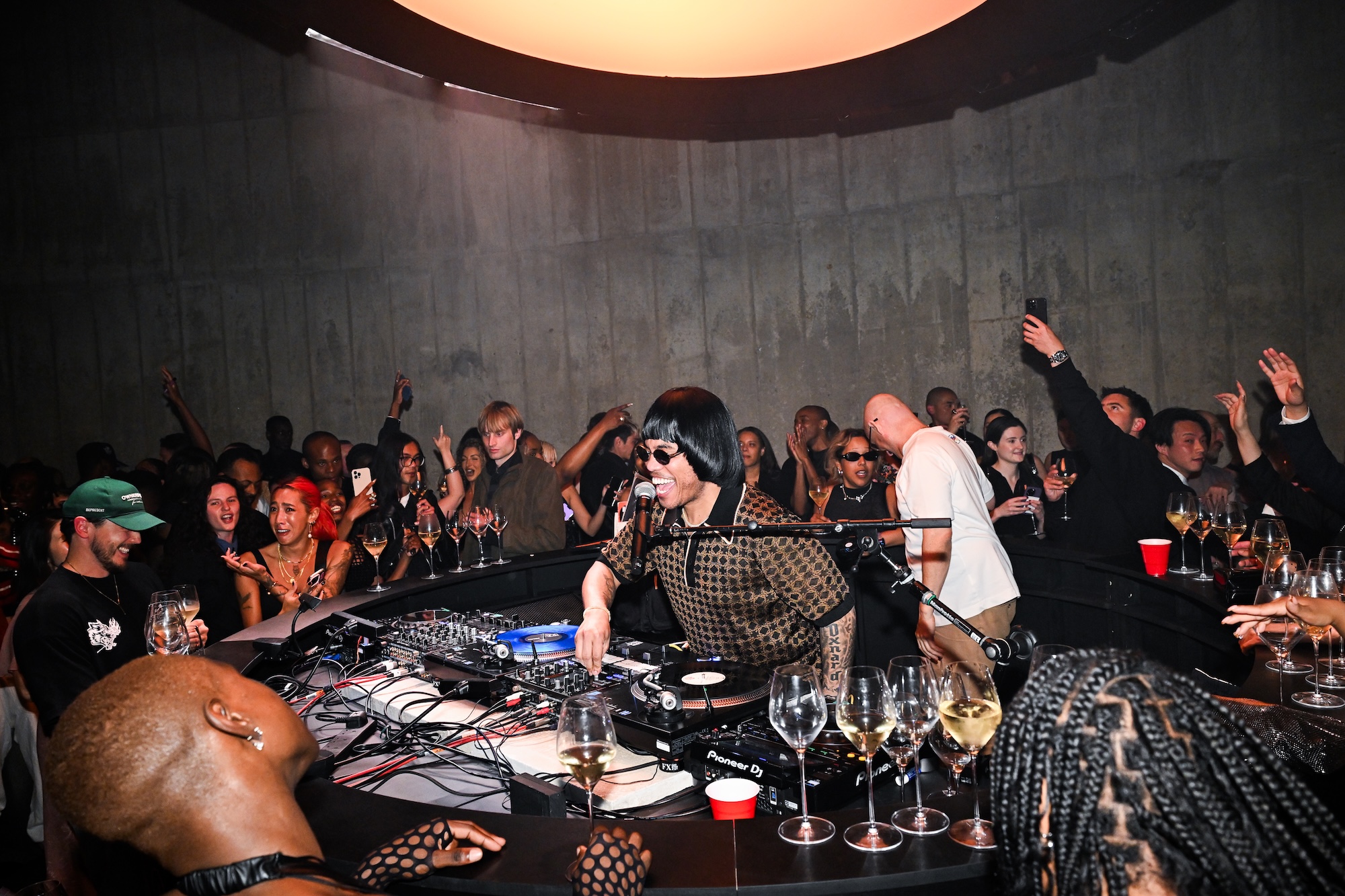 DJ playing music in a lively nightclub surrounded by a crowd enjoying the atmosphere.
