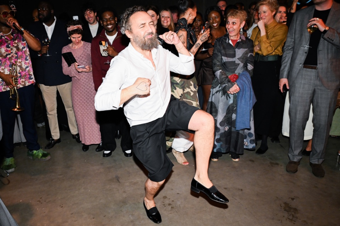 Man dancing energetically in a room full of people celebrating at a lively party or event indoors.