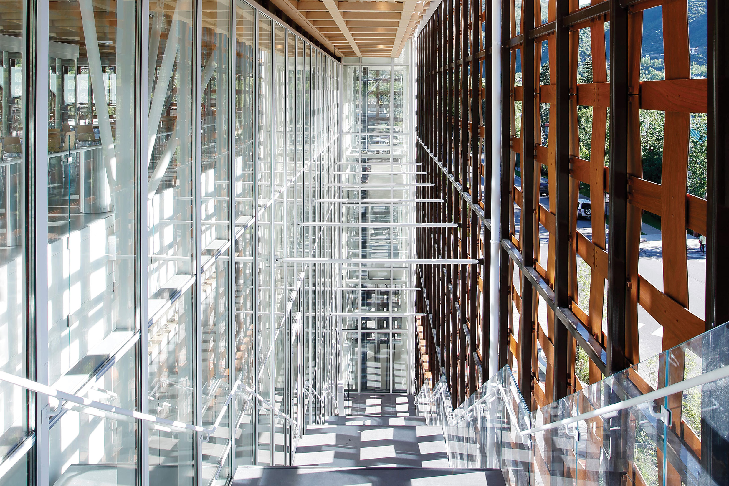 Spacious modern building interior with glass walls, wooden accents, and a bright, sunlit corridor.