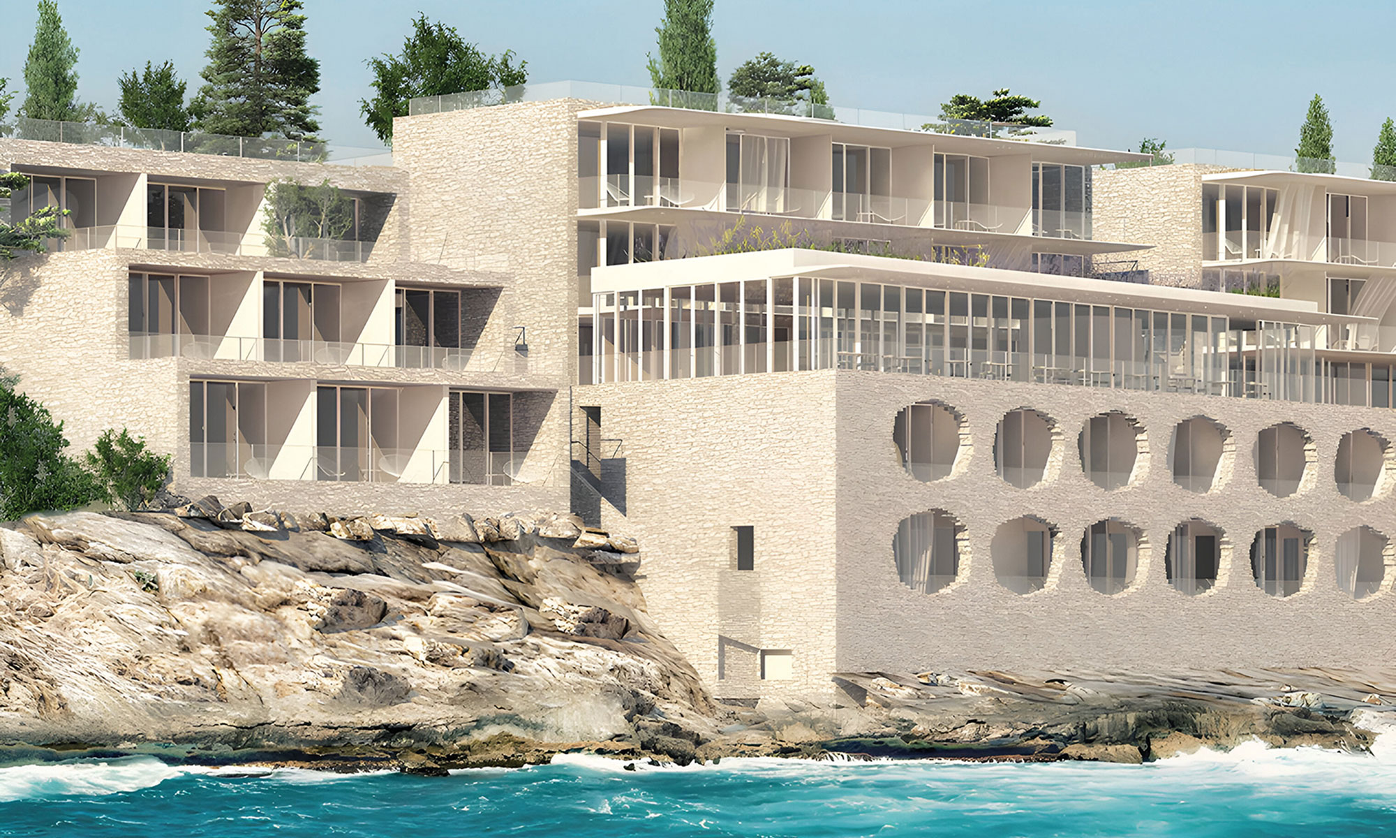 Modern cliffside hotel with balconies overlooking the ocean, built with light stone and surrounded by greenery.