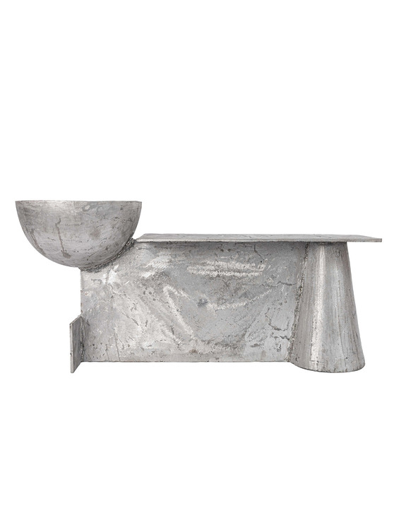 Modern, abstract metal sculpture with geometric shapes, featuring a bowl on the left and angular forms on the right.