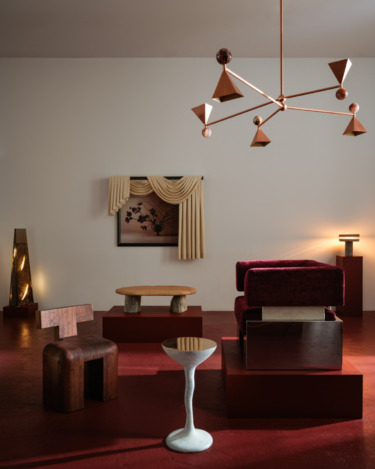 Modern living room with geometric furniture, chandelier, abstract art, red flooring, cozy lighting, and elegant beige drapes.