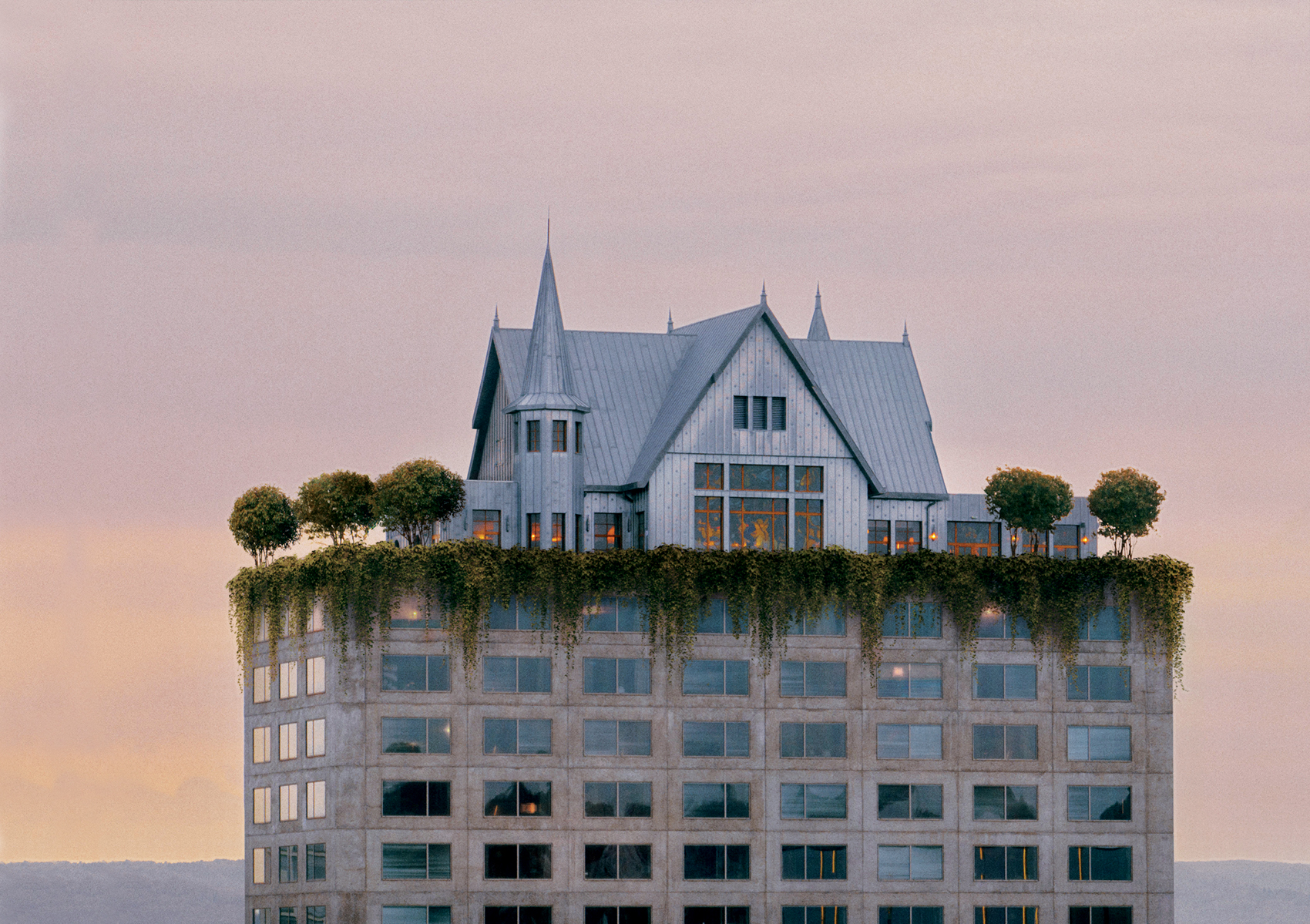 A modern building topped with a house-like structure and greenery-covered rooftop under a warm sky.