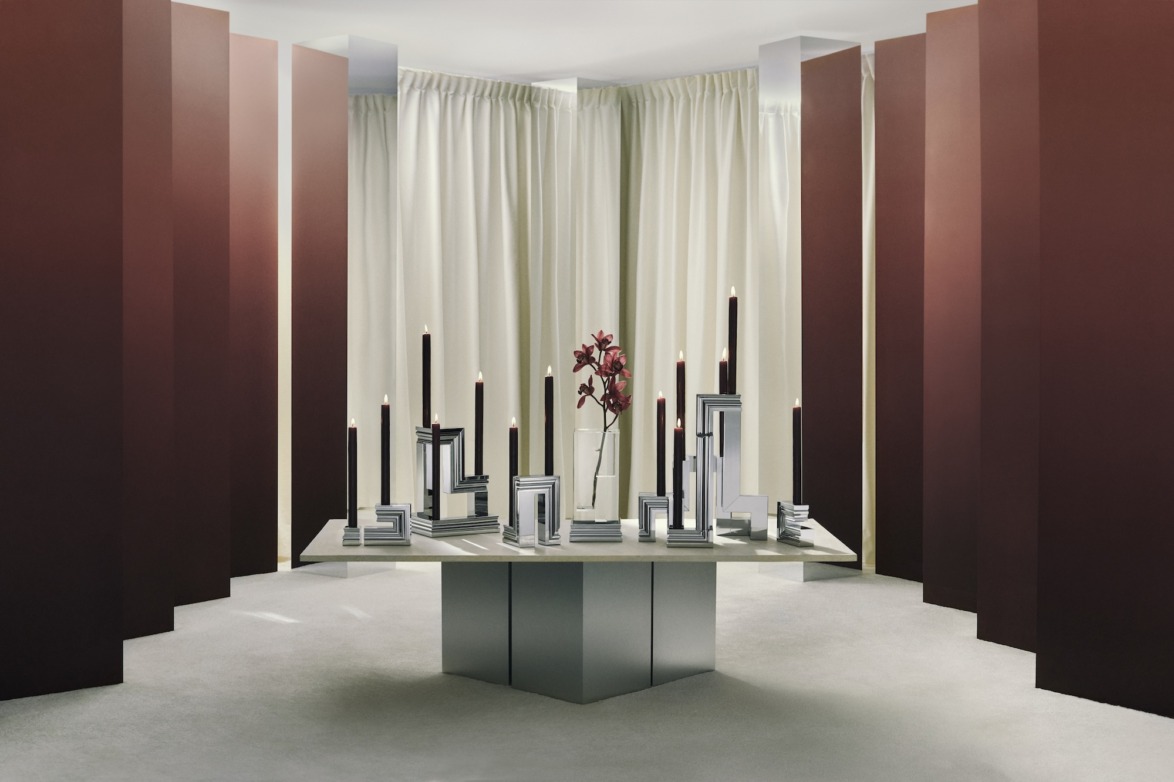 Modern dining room with geometric candleholders on a table, surrounded by tall maroon panels and beige curtains.