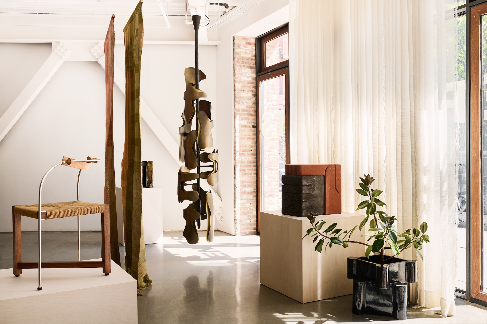 Modern art gallery interior with abstract sculptures, contemporary furniture, tall windows, and natural light.