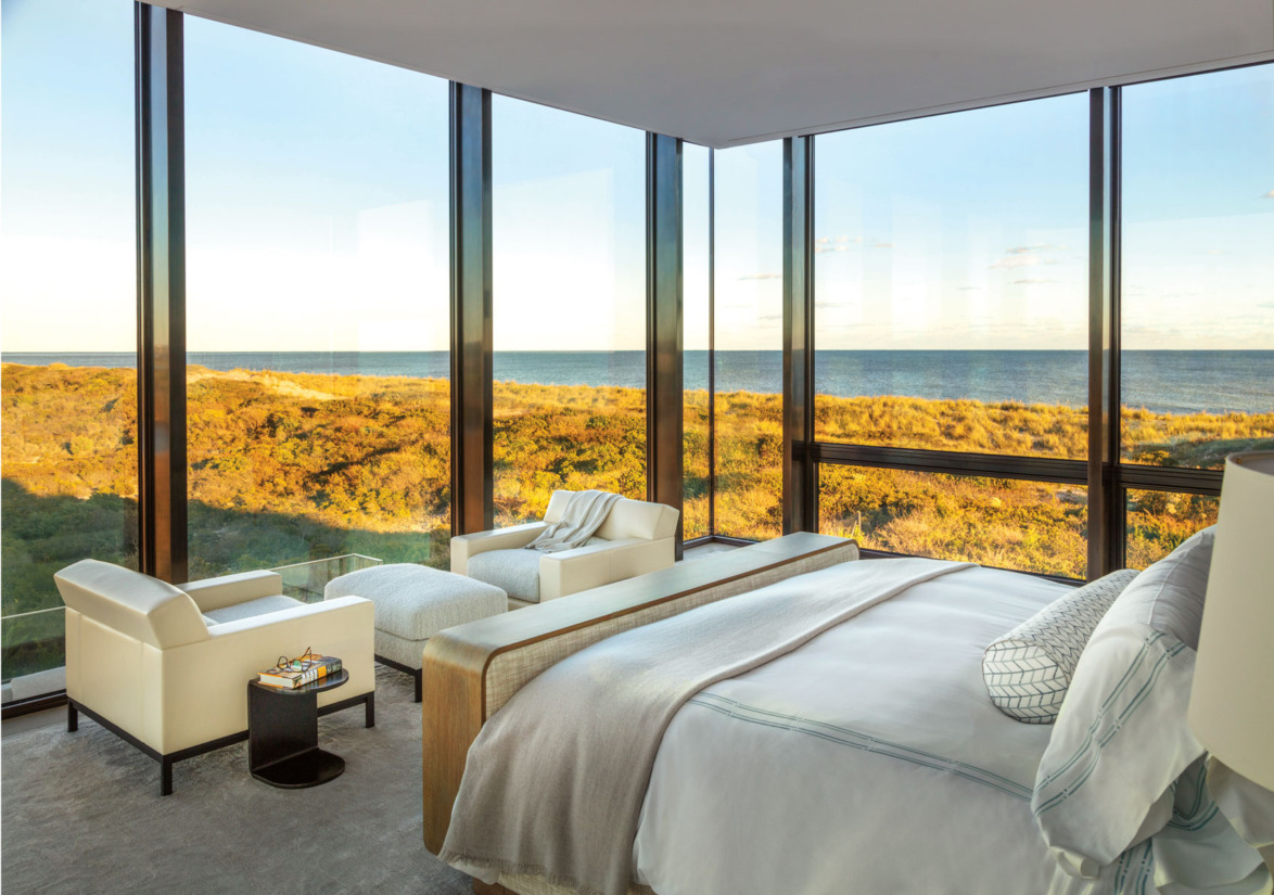 luxury bedroom with ocean view large windows comfortable bed and seating area overlooking a scenic coastal landscape
