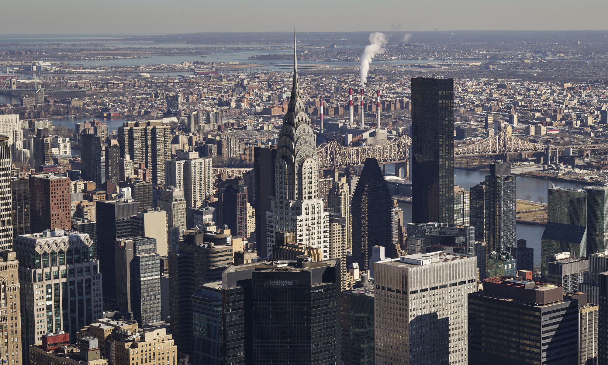 Aerial view of New York City skyline featuring the iconic Chrysler Building and surrounding skyscrapers on a clear day.