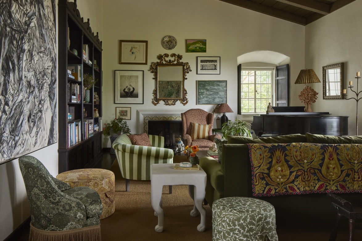 Eclectic living room with patterned chairs, a fireplace, and a bookshelf, creating a cozy and artistic atmosphere.