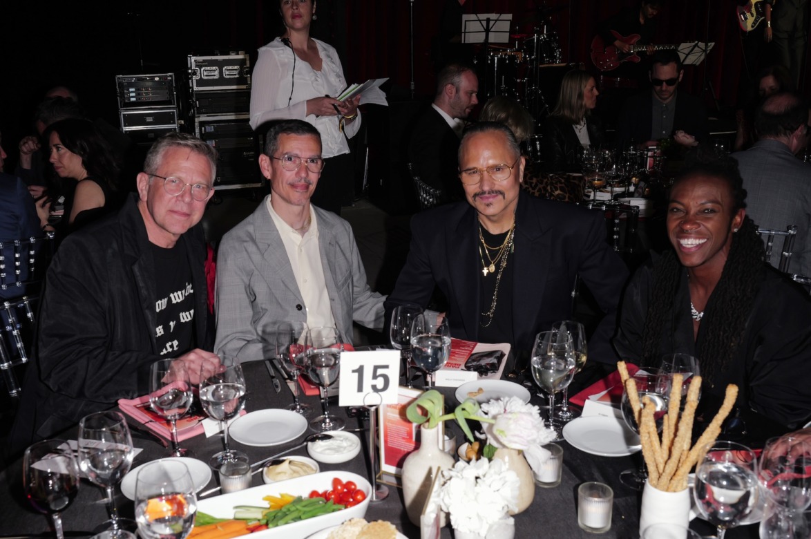 A group of people sitting around a table with plates of food and drinks at an event or gathering.