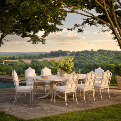 Outdoor dining set on a stone patio overlooking a scenic landscape with trees and distant hills.