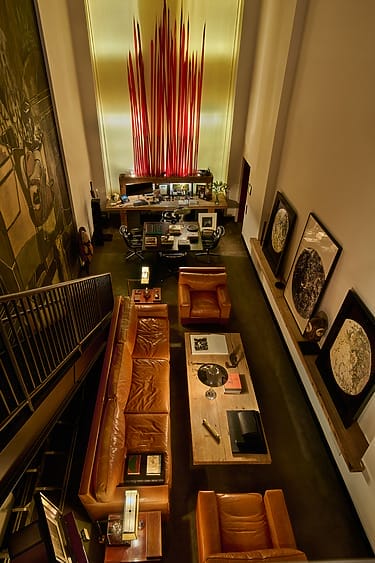 Modern living room with leather sofas, abstract wall art, and a dramatic vertical red sculpture centerpiece.