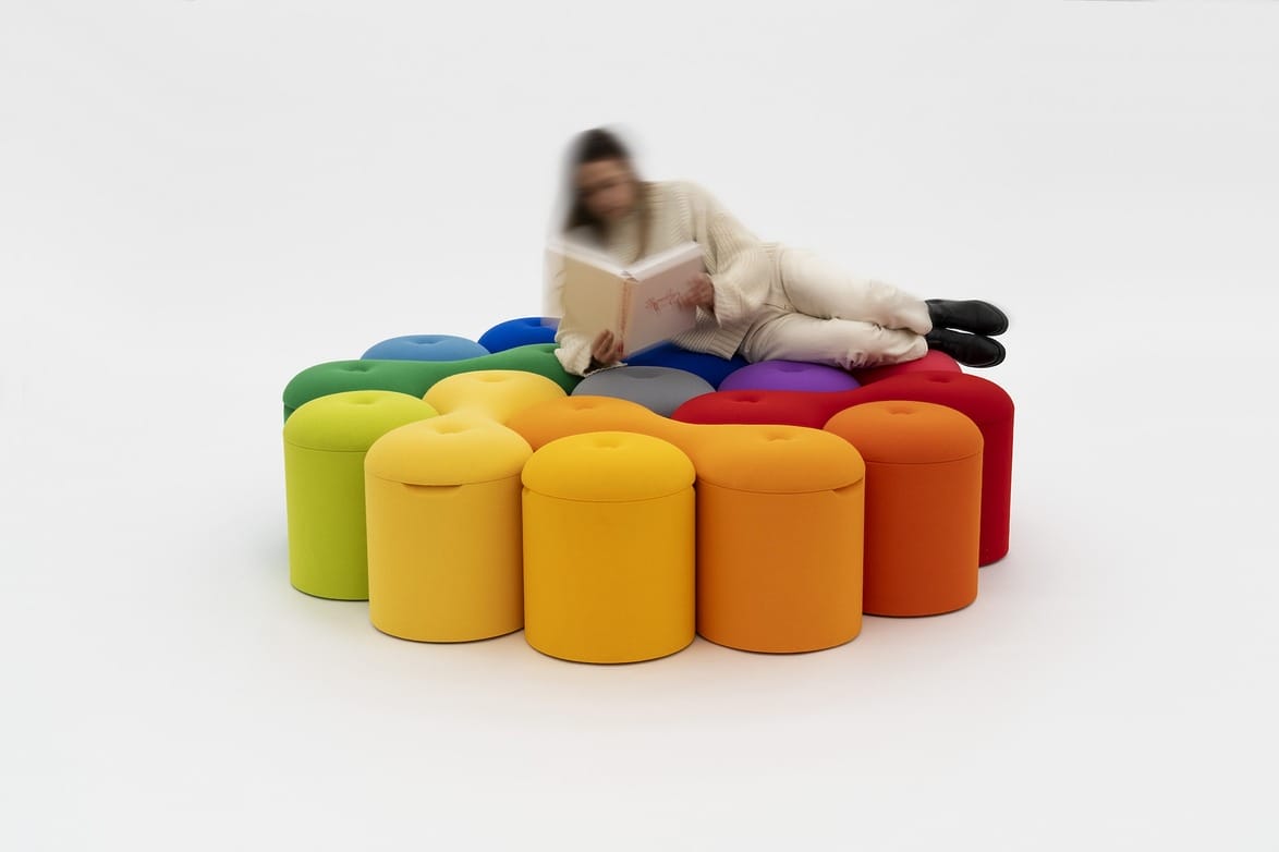 Person reading on colorful, round stools arranged in a circle on a white background.