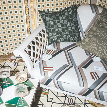 Stylish lounge area with patterned sofa, decorative pillows, playing cards, and glasses on a geometric table.