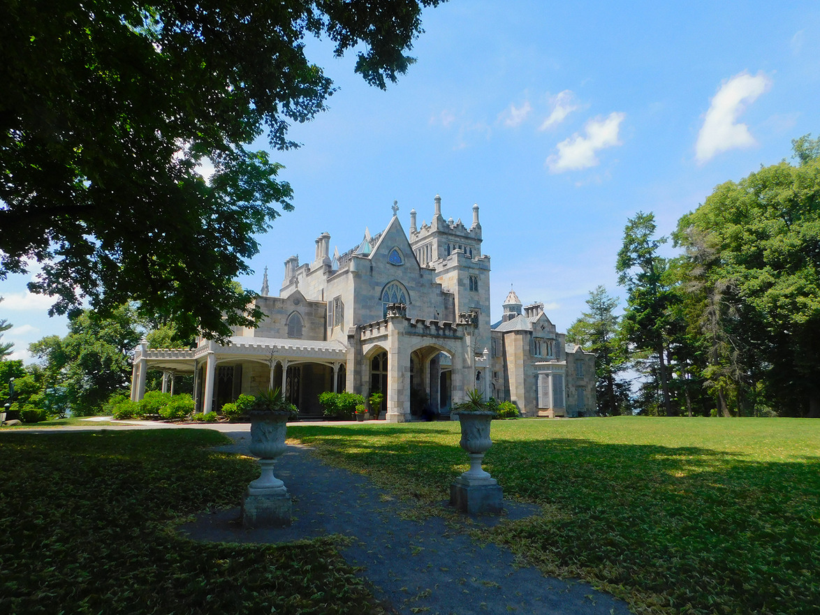 Historic Gothic-style mansion surrounded by trees under a clear blue sky.