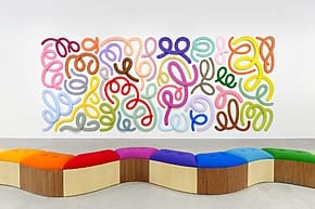 Colorful abstract wall art with swirling patterns above a wavy, multicolored bench in a modern gallery setting.