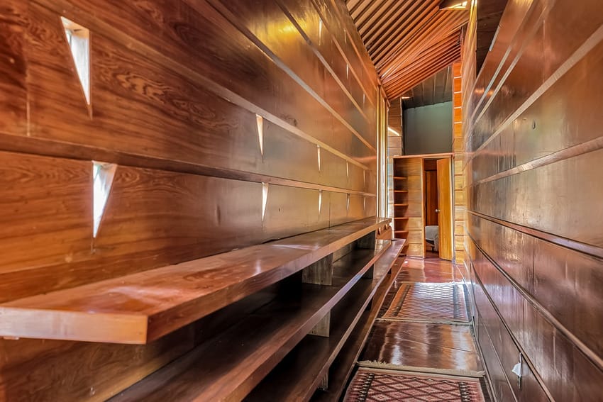 Warm wooden hallway with slanted ceiling and built-in shelving, creating a cozy and inviting atmosphere.