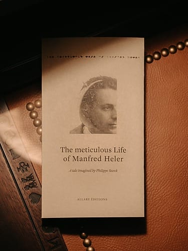 Book titled "The Mysterious Life of Manfred Herbst" on a leather surface with a portrait of a man.