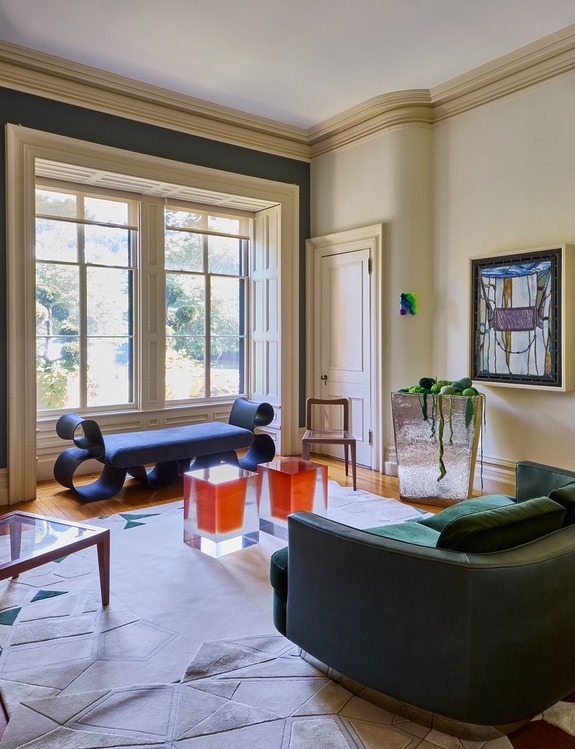 Elegant living room with modern furniture, large window, abstract art, and natural light illuminating the space.