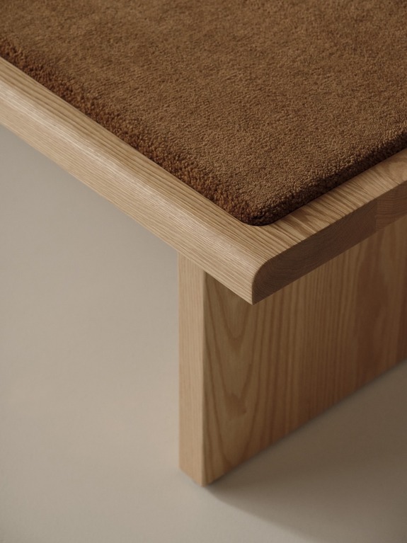 Modern wooden table with a smooth light brown surface and a close-up view of its sturdy legs and textured top edge.