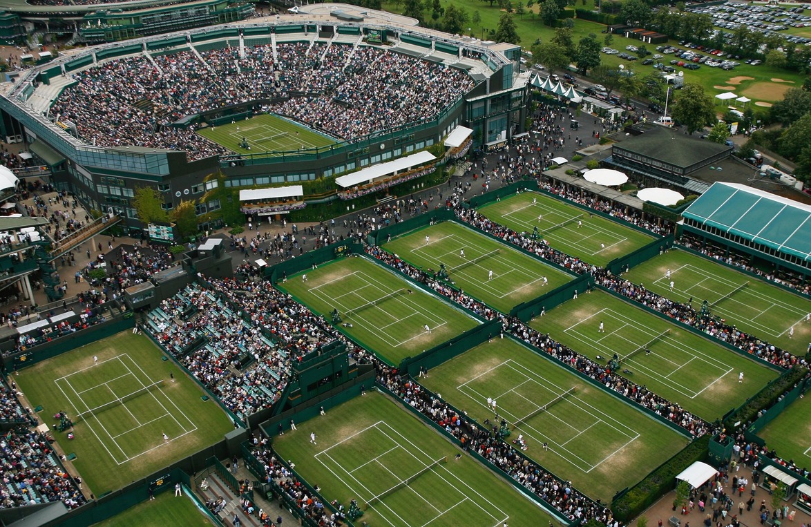 Aerial view of a tennis tournament with multiple courts and a large crowd in a stadium.
