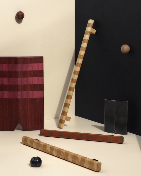 Wooden abstract art pieces and geometric shapes arranged on a textured surface with a black and maroon color scheme.