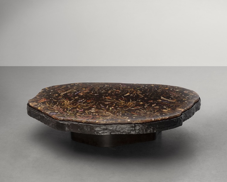 Unique dark wood coffee table with artistic patterns on the surface, set against a plain grey background.