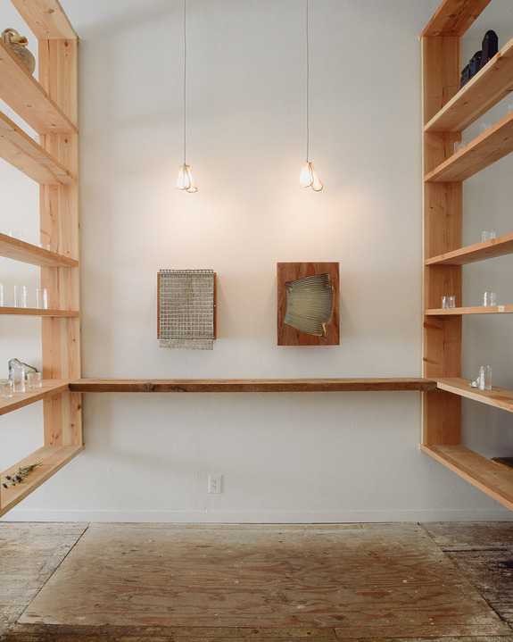 Minimalist room with wooden shelves, two pendant lights, and abstract art on the wall.
