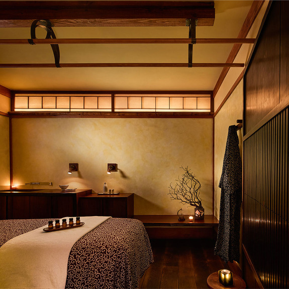 Tranquil spa room with dim lighting, massage tables, candles, and peaceful decor enhancing a serene ambiance.