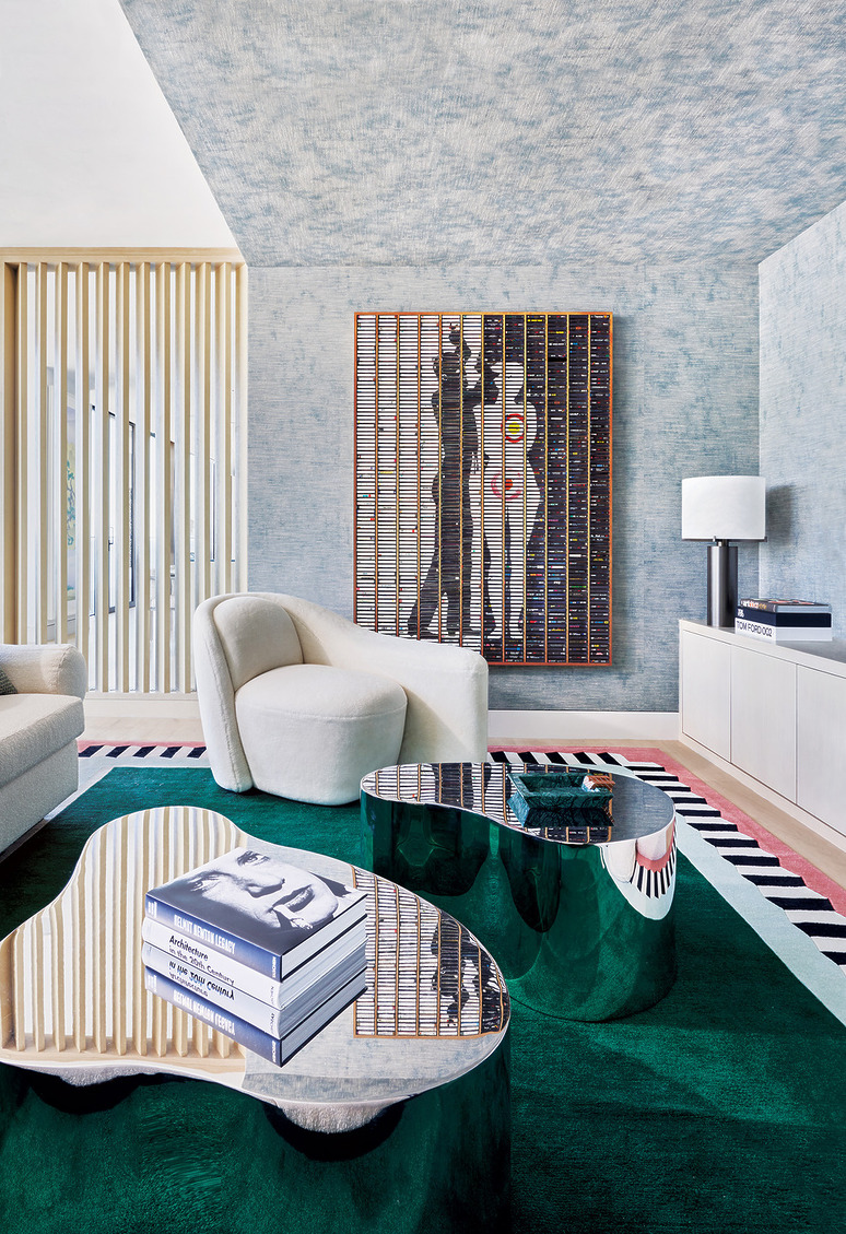 Modern living room with abstract art, plush seating, and glossy coffee tables on a green rug, creating a stylish atmosphere.