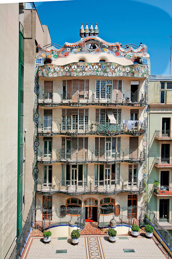 Colorful, ornate building facade with intricate designs and balconies against a clear blue sky.