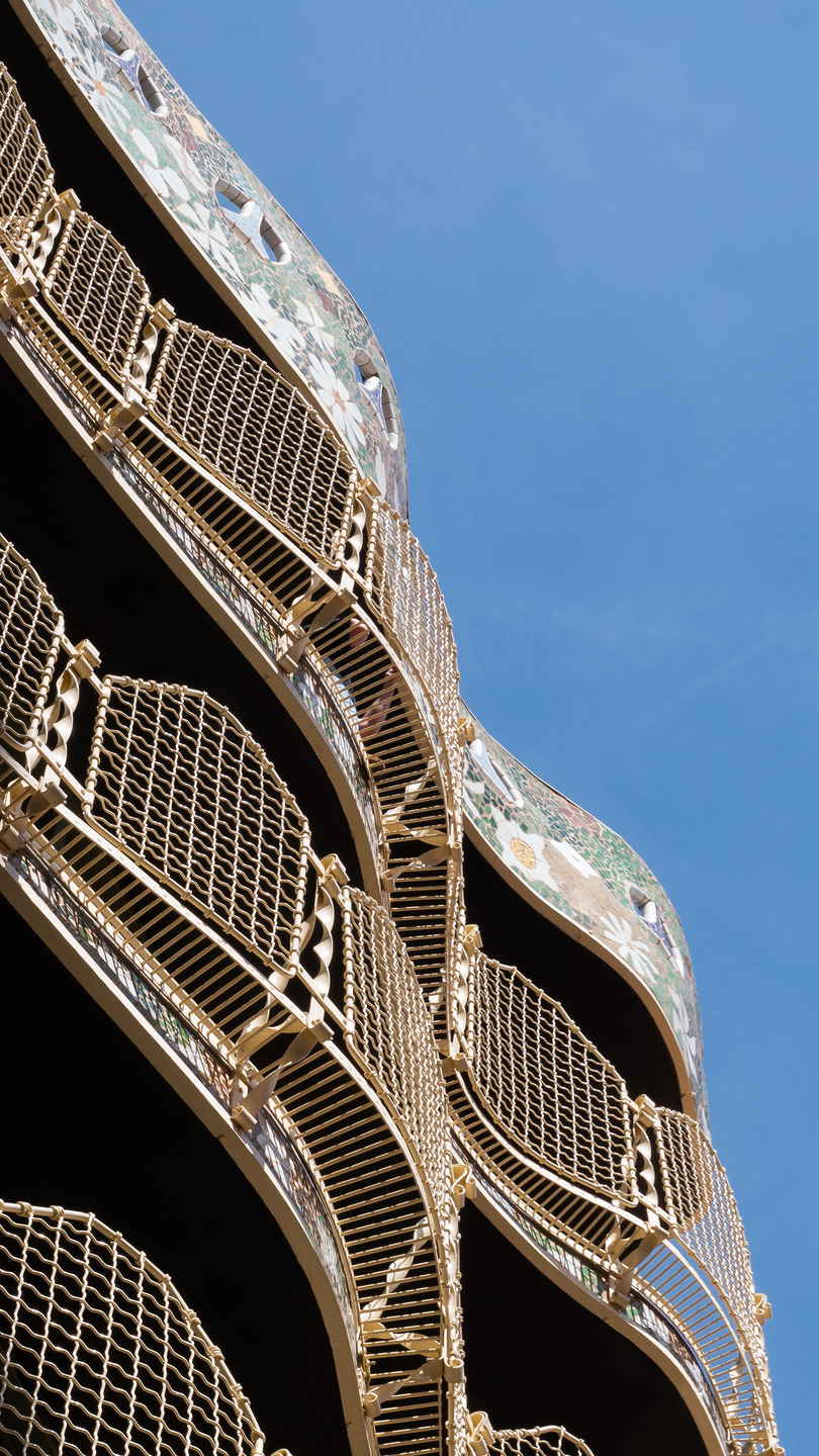 Curved balconies with ornate gold railings against a clear blue sky.