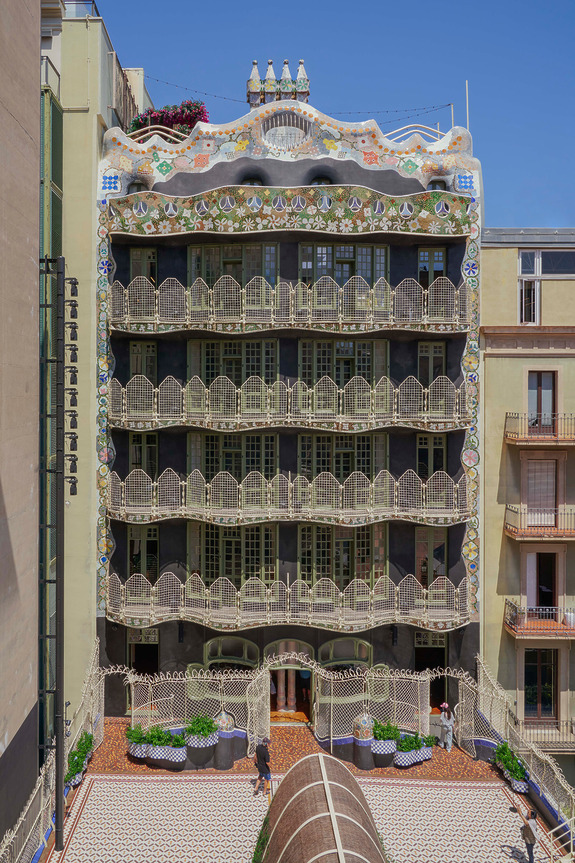 Colorful, ornate facade of Casa Batlló in Barcelona, featuring curved lines and mosaic details under a clear blue sky.